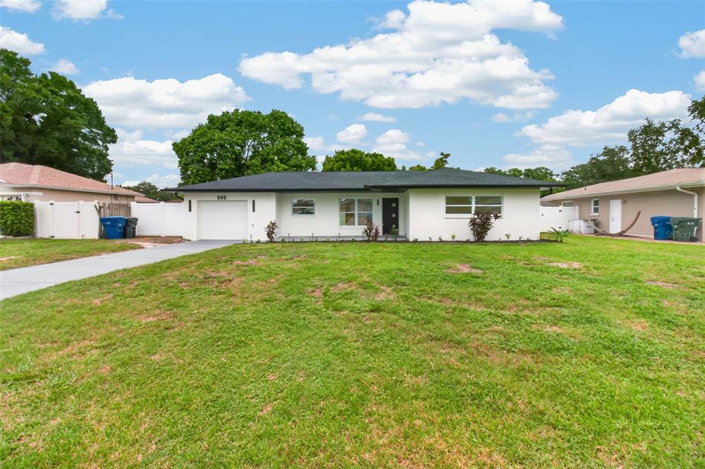 A single-story white house with a black roof and a front-facing garage — 599 WOODLAND DRIVE, LARGO, FL