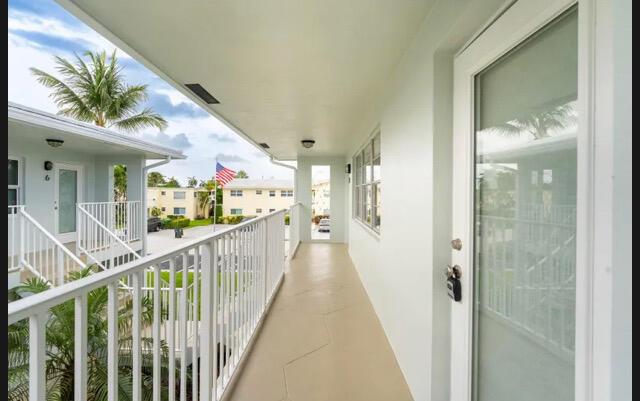 An outdoor walkway with white railings leads to a glass-paneled door in a residential building — 2737 NE 28th Street # 9w, Lighthouse Point FL 33064, LIGHTHOUSE POINT, FL