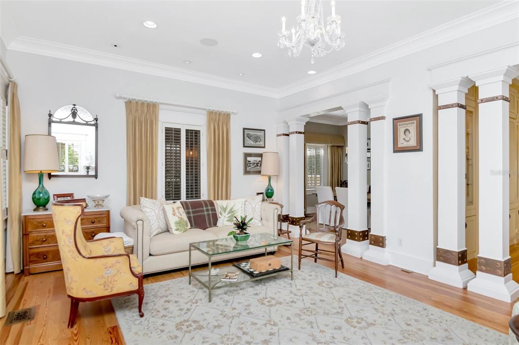 A living room features a chandelier, white columns, hardwood floors, and a beige sofa — 713 S DELAWARE AVENUE, TAMPA, FL