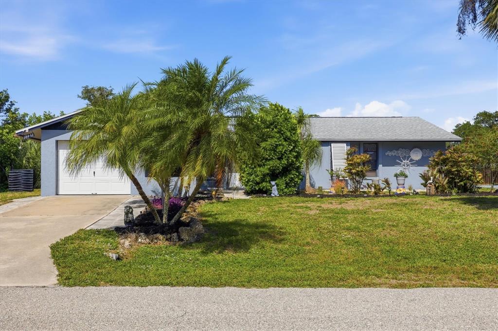 A white front door with a black wreath is centered on a light gray exterior wall — 18461 BURKHOLDER CIRCLE, PORT CHARLOTTE, FL