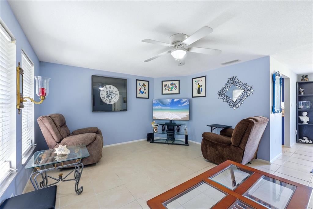 A living room features light blue walls, a red sofa, a brown recliner, and tile flooring — 18461 BURKHOLDER CIRCLE, PORT CHARLOTTE, FL