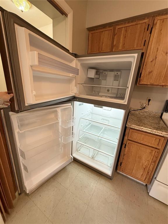 An open refrigerator stands in a kitchen with wooden cabinets and a granite countertop — 615 SW 11TH LANE UNIT D, GAINESVILLE, FL