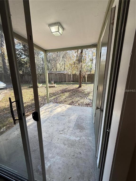 A concrete patio with a ceiling light overlooks a backyard through a sliding glass door — 615 SW 11TH LANE UNIT D, GAINESVILLE, FL