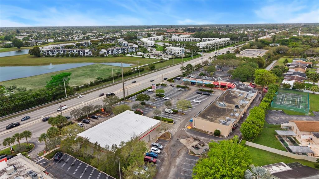 An aerial view shows a commercial strip mall with a parking lot beside a road — 4608 S JOG ROAD, GREENACRES, FL