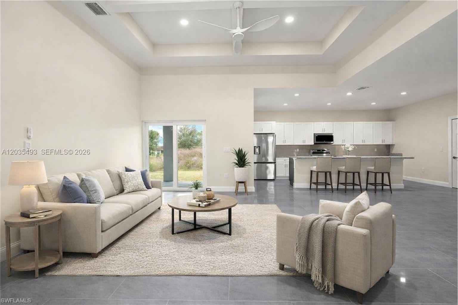 A spacious open-concept living room features a tray ceiling, tile flooring, and an adjacent kitchen — 1043 albert ave # 1043, Lehigh Acres FL 33971, LEHIGH ACRES, FL