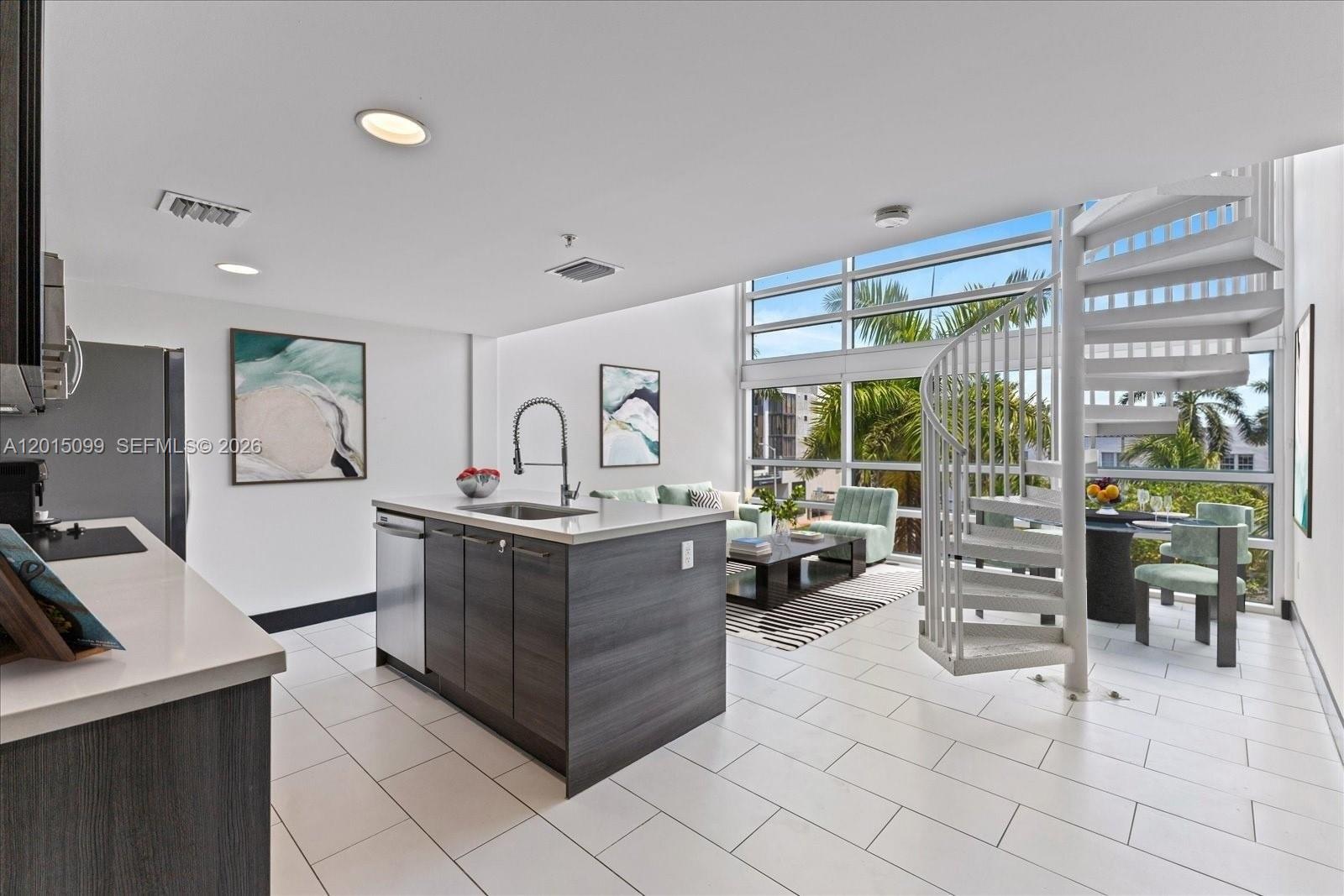 A modern kitchen and living area features a spiral staircase, floor-to-ceiling windows, and tile flooring — 421 Meridian Ave # 19, Miami Beach FL 33139, MIAMI BEACH, FL