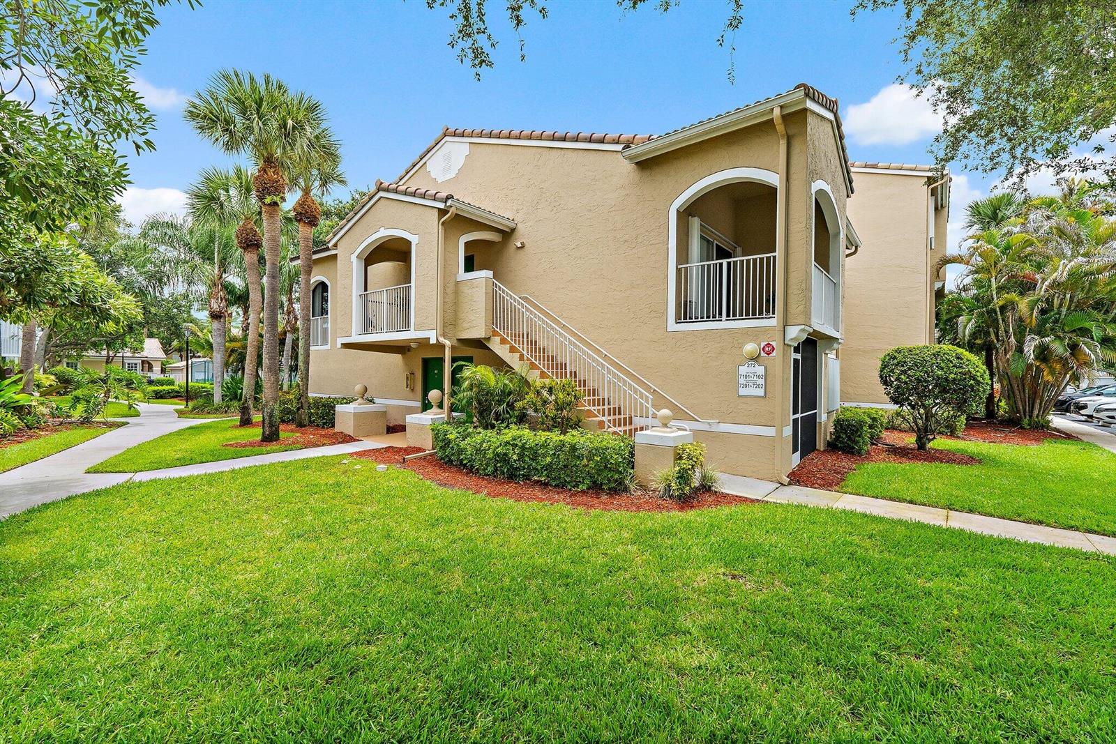 A two-story tan stucco apartment building features an exterior staircase and balconies — 272 Village Boulevard # 7102, Tequesta FL 33469, TEQUESTA, FL