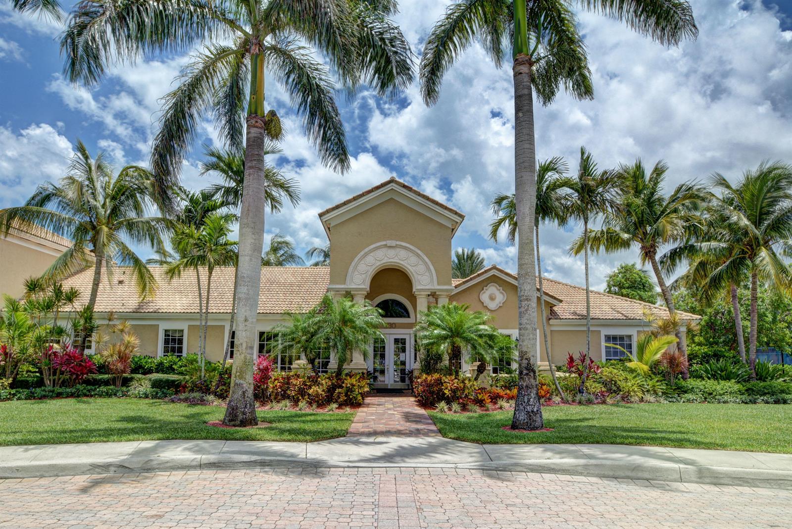 A beige single-story building with a tiled roof is framed by tall palm trees — 272 Village Boulevard # 7102, Tequesta FL 33469, TEQUESTA, FL