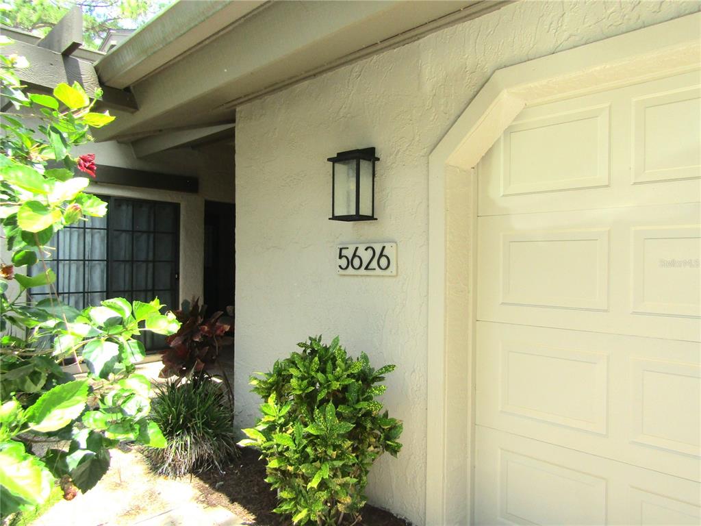 A beige exterior wall features a black wall sconce and the house number 5626 — 5626 PIPERS WAITE UNIT 22, SARASOTA, FL