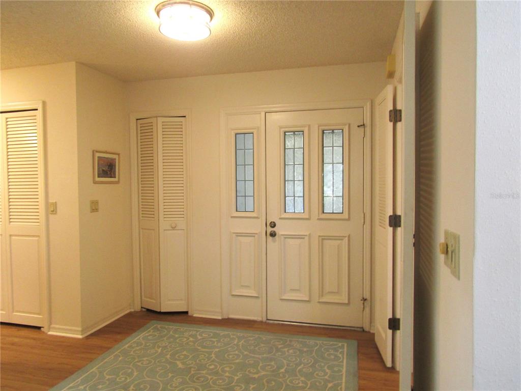 An entryway features a light-colored front door with glass panels, louvered closets, and wood flooring — 5626 PIPERS WAITE UNIT 22, SARASOTA, FL