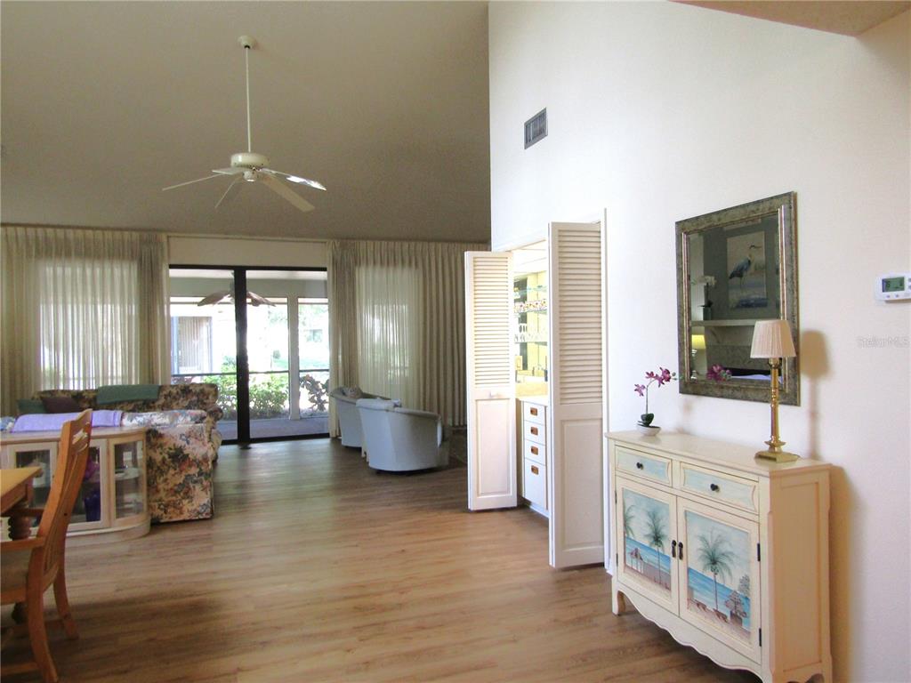 A living room features light wood flooring, a ceiling fan, and a painted storage cabinet — 5626 PIPERS WAITE UNIT 22, SARASOTA, FL