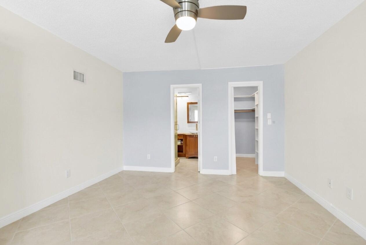A bedroom with light-colored tile flooring, a ceiling fan, and two doorways leading to rooms — 1850 S Ocean Boulevard # 304, Pompano Beach FL 33062, POMPANO BEACH, FL
