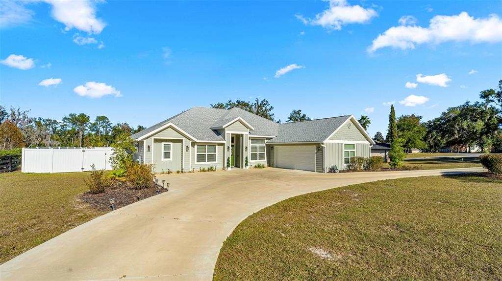 A light green single-story house with a gray roof and a long concrete driveway — 479 NW SAVANNAH CIRCLE, LAKE CITY, FL