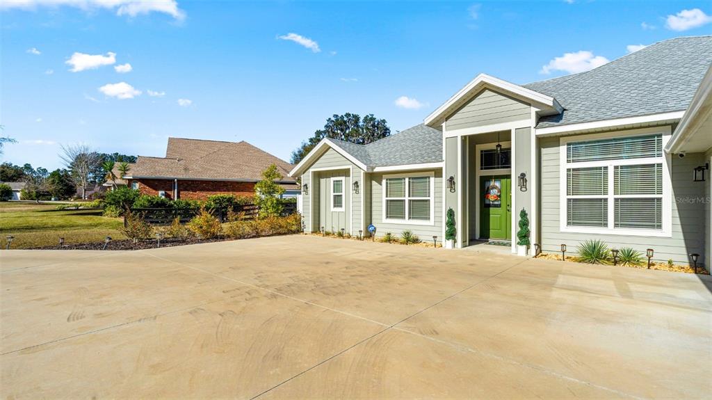 A light green house with a concrete driveway and a green front door — 479 NW SAVANNAH CIRCLE, LAKE CITY, FL