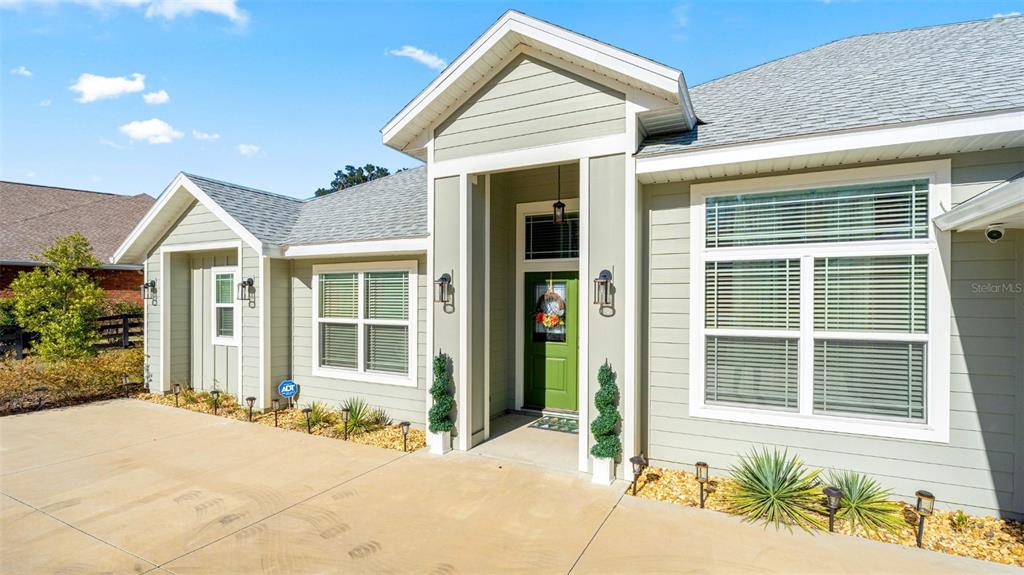 The exterior of a light green house features a covered entryway and a concrete driveway — 479 NW SAVANNAH CIRCLE, LAKE CITY, FL