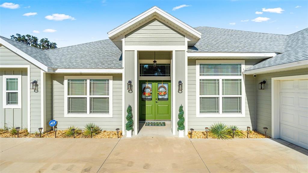 The exterior of a light green house features a double green front door and driveway — 479 NW SAVANNAH CIRCLE, LAKE CITY, FL