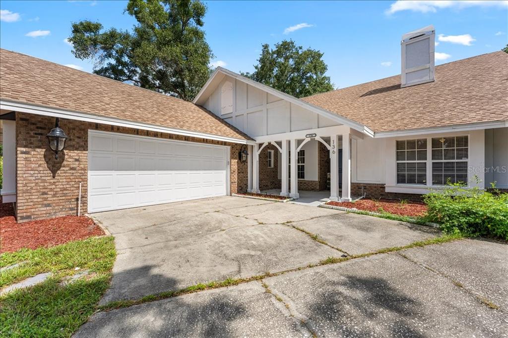 A single-story house with a brick and white exterior, a two-car garage, and a driveway — 136 SHEFFIELD CIRCLE E, PALM HARBOR, FL