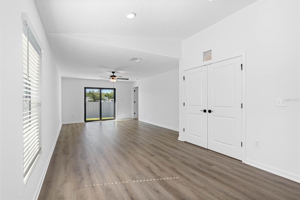 An empty room with white walls, wood-look flooring, a ceiling fan, and double closet doors — 13053 TRAPPER JOHN ROAD, WEEKI WACHEE, FL
