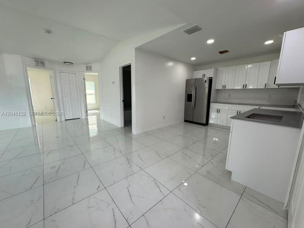 A bright kitchen features white cabinets, stainless steel appliances, and white marble-patterned tile flooring — 732 Ichabod Ave # 732, Lehigh Acres FL 33973, LEHIGH ACRES, FL