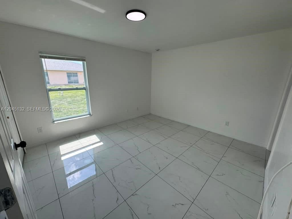 A bedroom with white walls, a single window, and light-colored marble-patterned tile flooring — 732 Ichabod Ave # 732, Lehigh Acres FL 33973, LEHIGH ACRES, FL