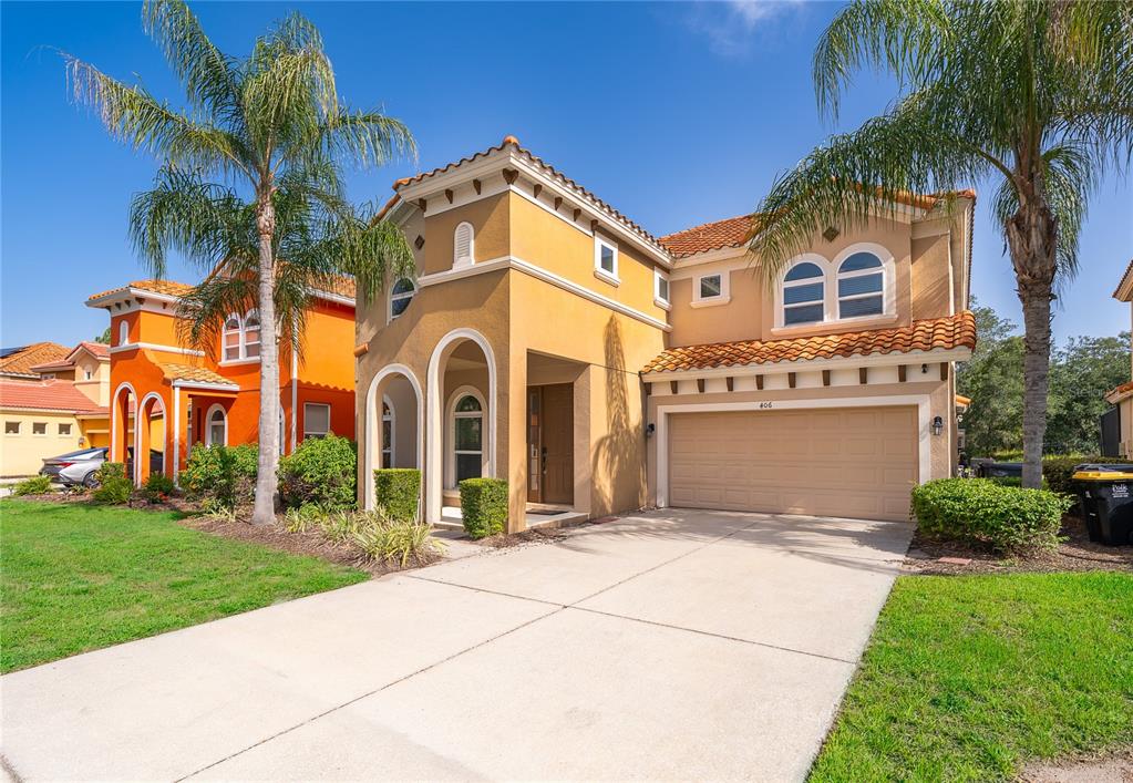 A two-story tan stucco house with a tile roof and a two-car garage — 406 ORANGE COSMOS BOULEVARD, DAVENPORT, FL