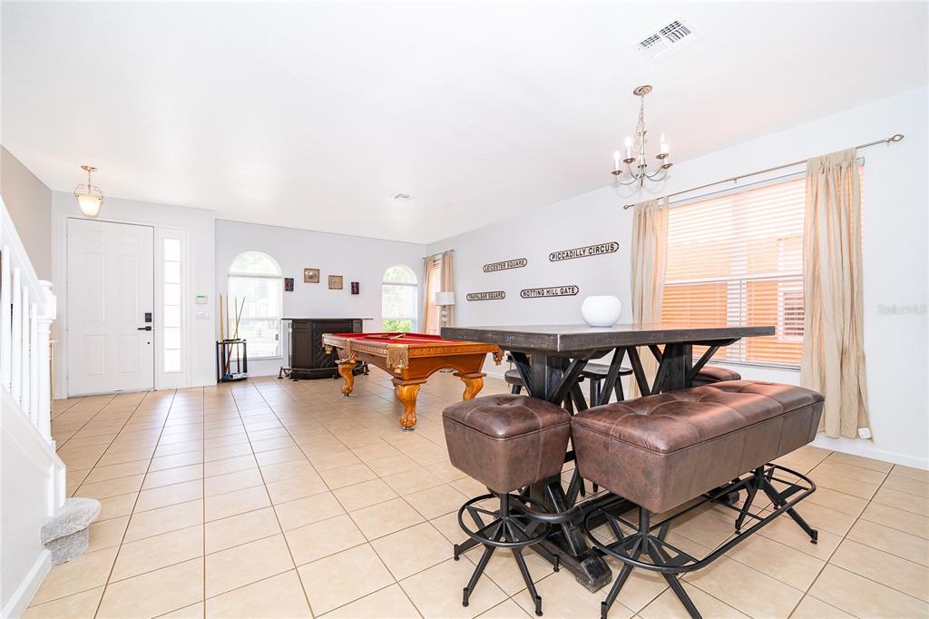 A spacious room with tile flooring features a pool table and a high-top dining set — 406 ORANGE COSMOS BOULEVARD, DAVENPORT, FL
