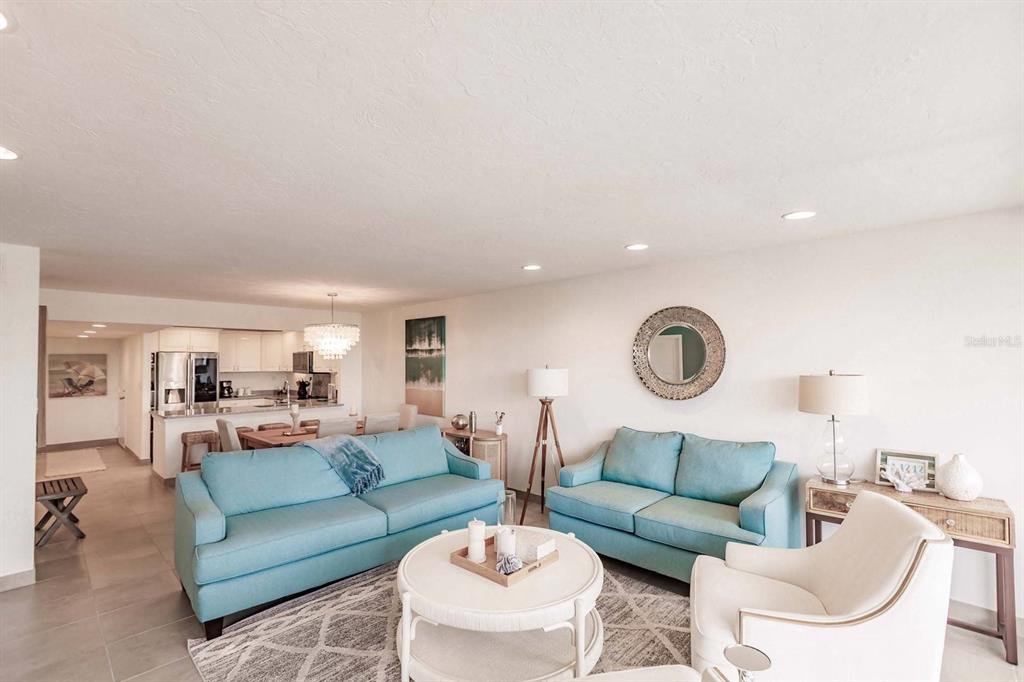 A living room features two light blue sofas, a white coffee table, and a kitchen area — 1125 W PEPPERTREE DRIVE UNIT 407, SARASOTA, FL