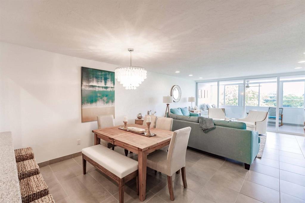 A dining area with a wooden table and chairs sits adjacent to a living room — 1125 W PEPPERTREE DRIVE UNIT 407, SARASOTA, FL