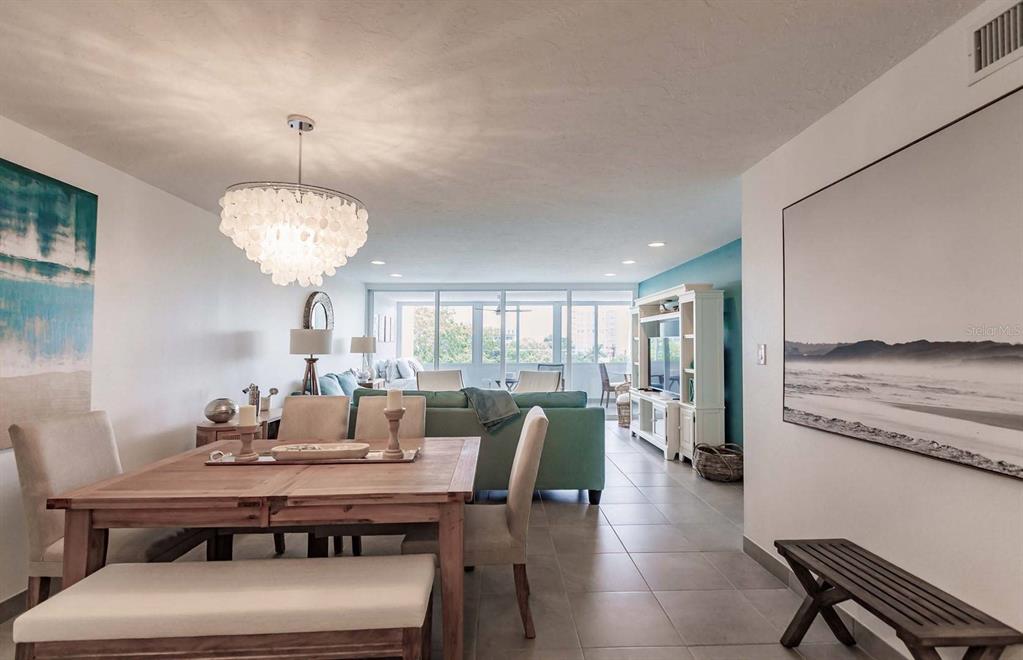 A dining area with a wooden table and chandelier opens into a living room — 1125 W PEPPERTREE DRIVE UNIT 407, SARASOTA, FL