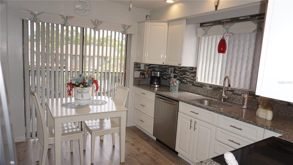 A kitchen features white cabinets, granite countertops, stainless steel appliances, and an adjacent dining area — 12805 WEDGEWOOD WAY UNIT C, HUDSON, FL
