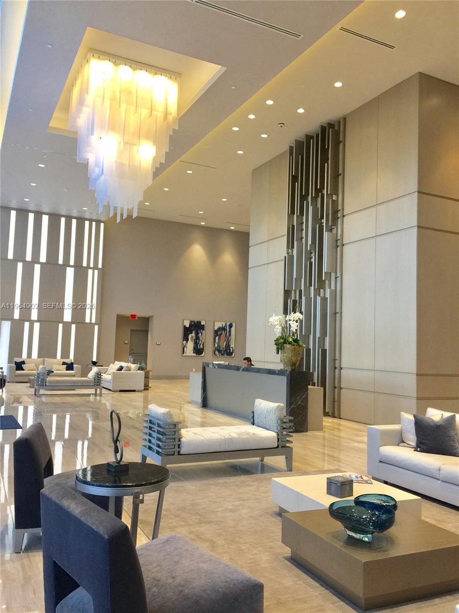A modern lobby features a large chandelier, a reception desk, and contemporary seating areas — 5300 Paseo Blvd # 410, Doral FL 33178, DORAL, FL