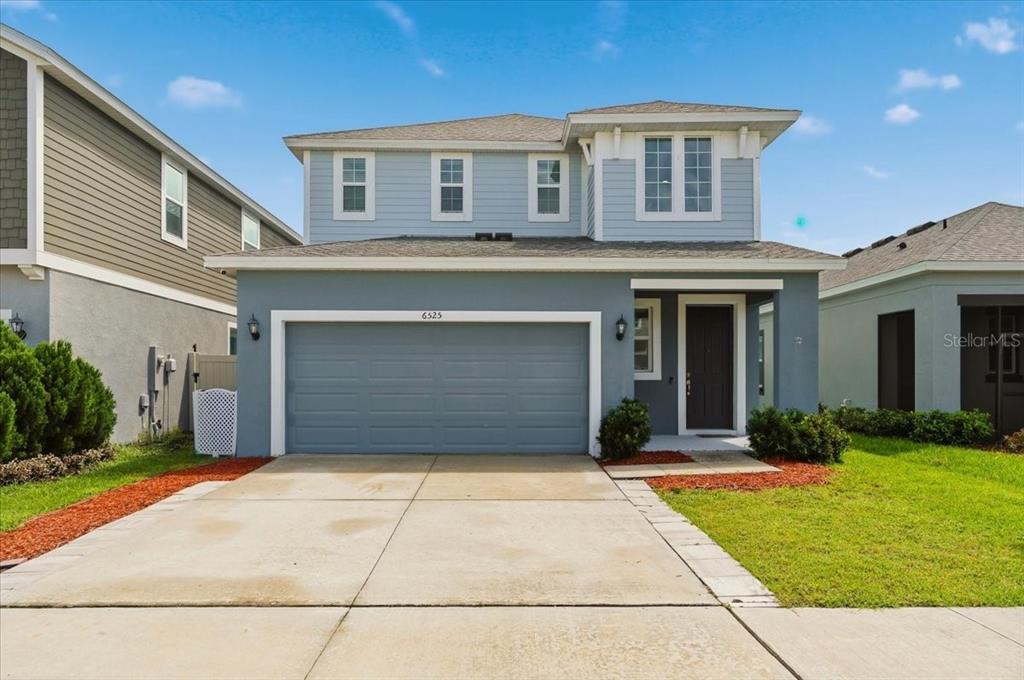 A two-story house with light blue siding, a two-car garage, and a concrete driveway — 6525 GREAT BEAR DRIVE, LAKELAND, FL