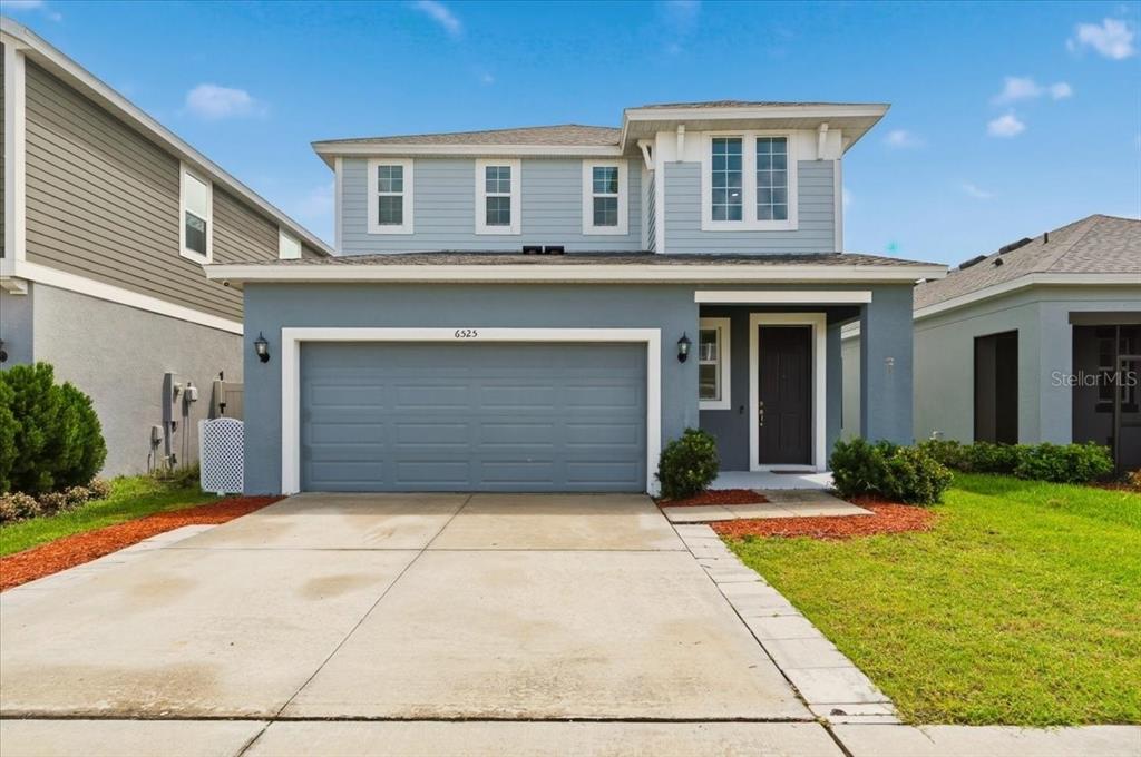 A two-story house with light blue siding, a two-car garage, and a front entrance — 6525 GREAT BEAR DRIVE, LAKELAND, FL