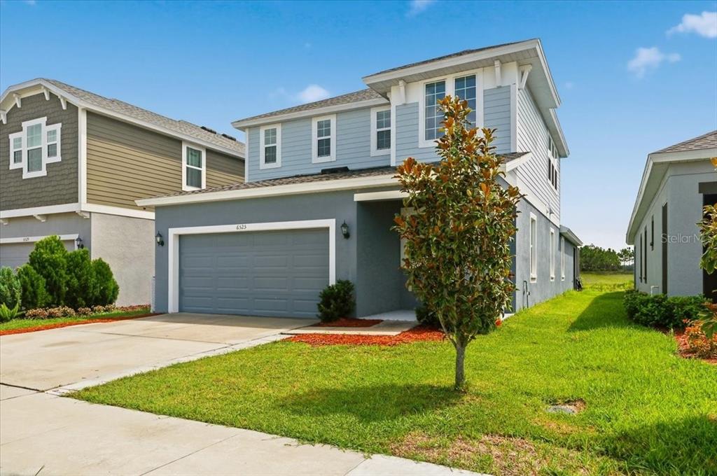 A two-story house with a gray garage, light blue siding, and a small front yard — 6525 GREAT BEAR DRIVE, LAKELAND, FL