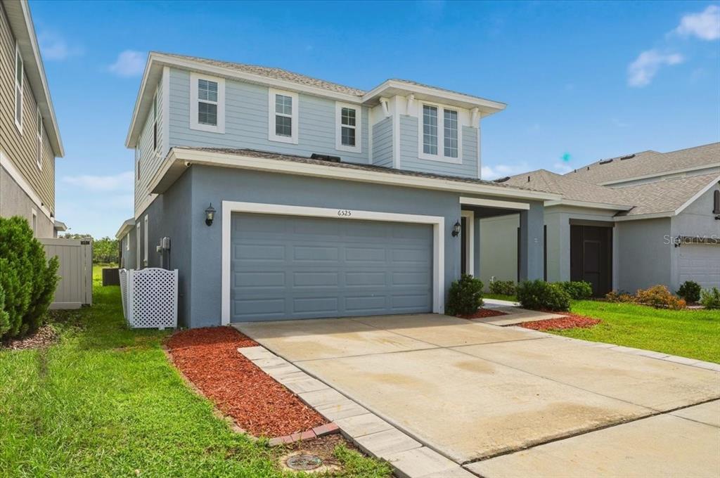 A two-story house with light blue siding, a gray garage, and a concrete driveway — 6525 GREAT BEAR DRIVE, LAKELAND, FL