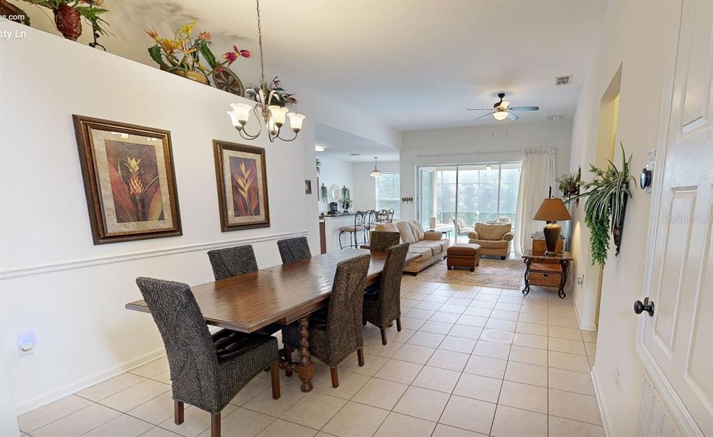 A dining area with a wooden table and chairs opens into a living room — 2706 MANESTY LANE, KISSIMMEE, FL