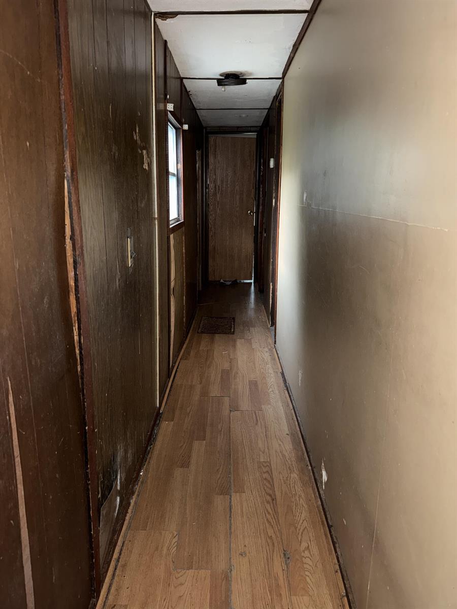 A narrow hallway features wood-paneled walls, a light-colored wall, and wood-look laminate flooring — 6072 SE 95th Trail, Okeechobee FL 34974, OKEECHOBEE, FL