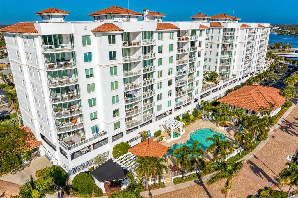 An aerial view of a multi-story white apartment building with balconies and a swimming pool — 1325 SNELL ISLE BOULEVARD NE UNIT 711, ST PETERSBURG, FL