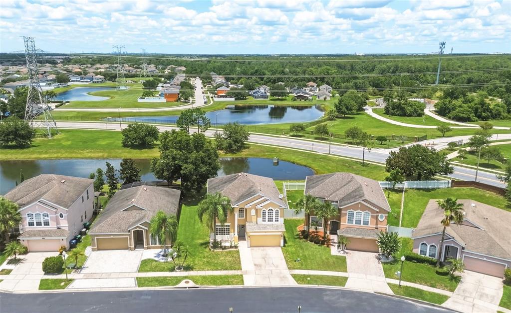 An aerial view shows a row of suburban houses facing a street and a pond — 1518 SUN MEADOW DRIVE, ORLANDO, FL