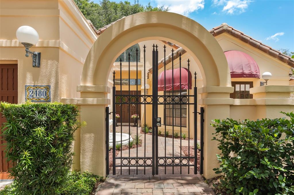 A gated courtyard entrance features a stone walkway, a fountain, and a stucco exterior — 2480 VIA GENOVA, APOPKA, FL