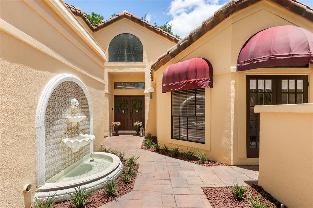 A courtyard entrance features a tiled wall fountain, stone walkway, and double front doors — 2480 VIA GENOVA, APOPKA, FL