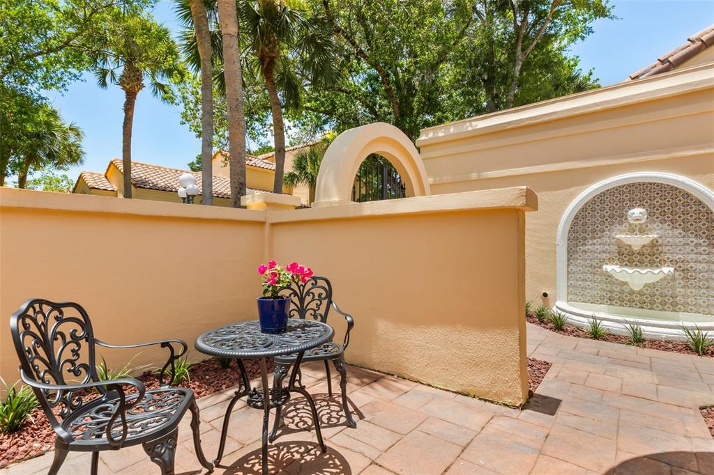 A patio features a metal table and chairs beside a decorative wall fountain — 2480 VIA GENOVA, APOPKA, FL