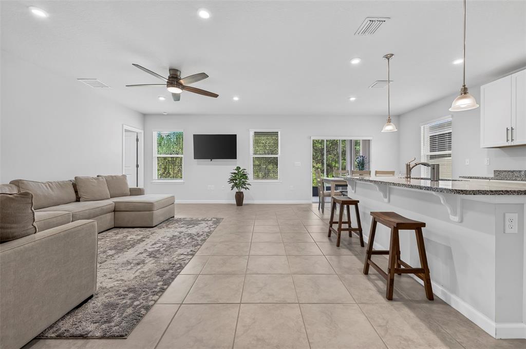 An open-concept living room and kitchen featuring tile floors, a sectional sofa, and bar seating — 306 EAGLE HARBOR WAY, DAYTONA BEACH, FL
