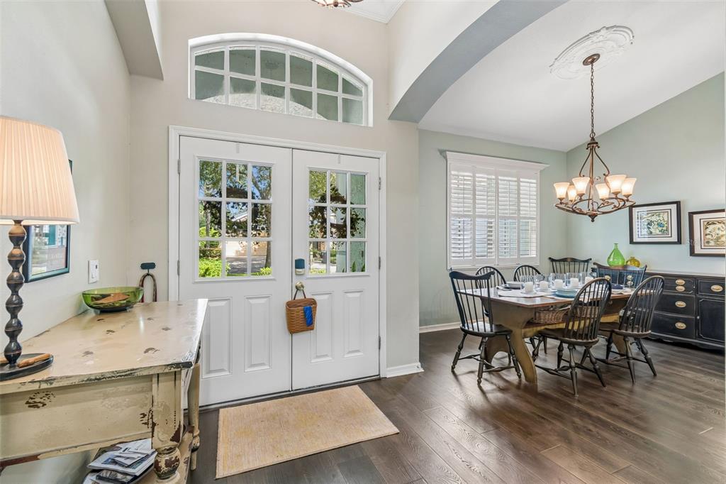 A dining room with dark wood floors, a chandelier, and a white double-door entryway — 3618 CORDGRASS DRIVE, VALRICO, FL