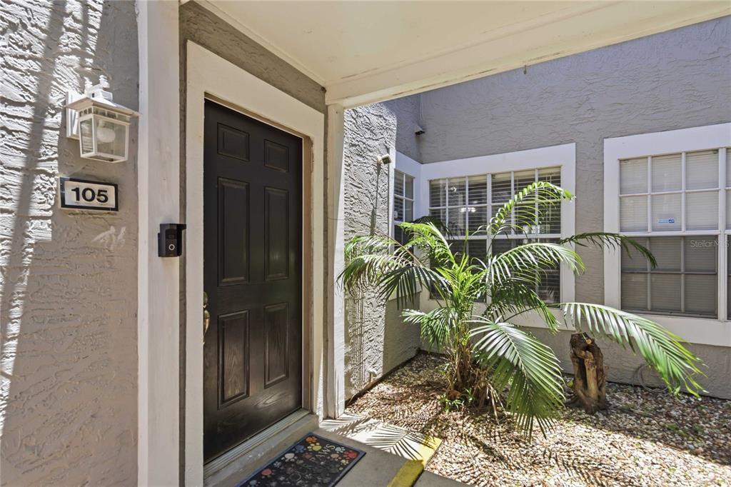 The exterior entrance features a black front door, a house number 105, and a palm plant — 1141 EXCELLER CT. UNIT 105, CASSELBERRY, FL