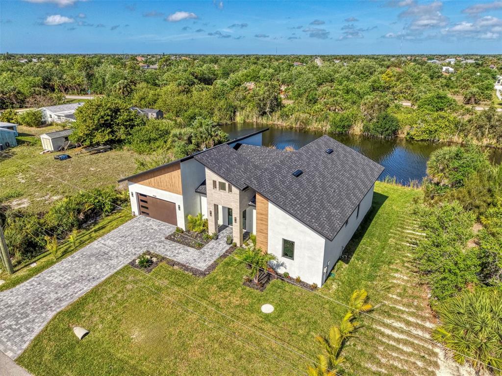 An aerial view of a modern house with a dark roof, stone accents, and a driveway — 9468 ATTICA CIRCLE, PORT CHARLOTTE, FL