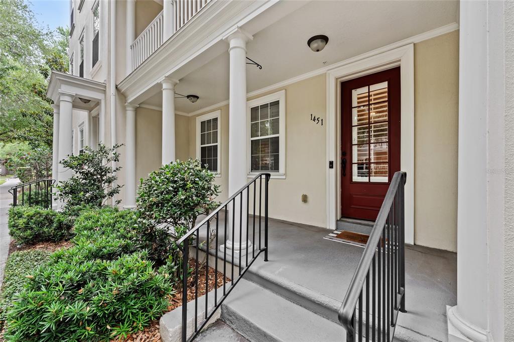 A covered porch with white columns leads to a red front door with glass panes — 1451 COMMON WAY ROAD, ORLANDO, FL