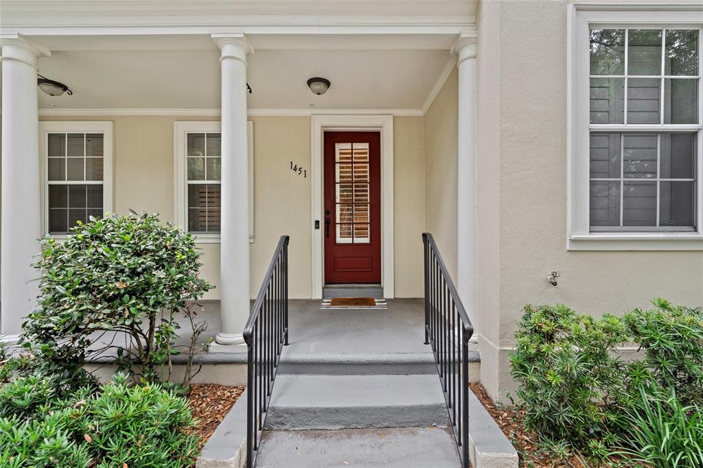 A red front door with a glass pane is centered on a covered porch with columns — 1451 COMMON WAY ROAD, ORLANDO, FL