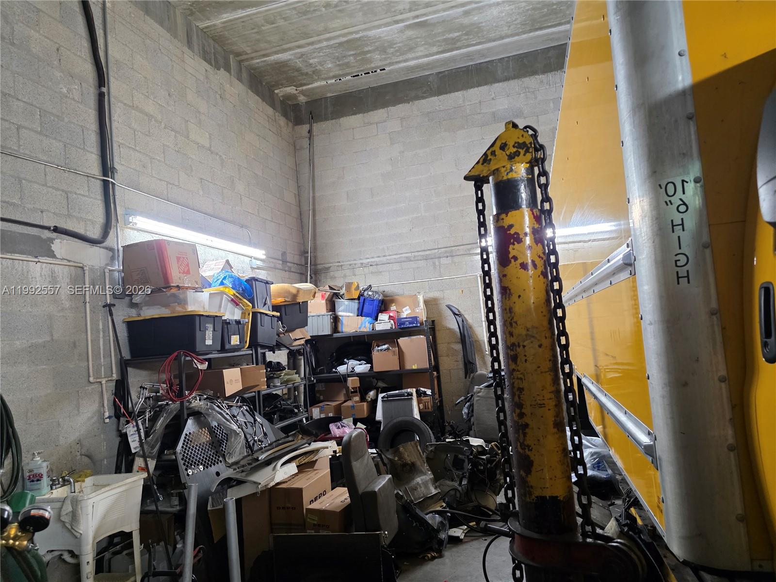 A cluttered industrial storage room features concrete block walls, shelving units, and a yellow truck — 16225 SW 117th Ave # 6, Miami FL 33177, MIAMI, FL