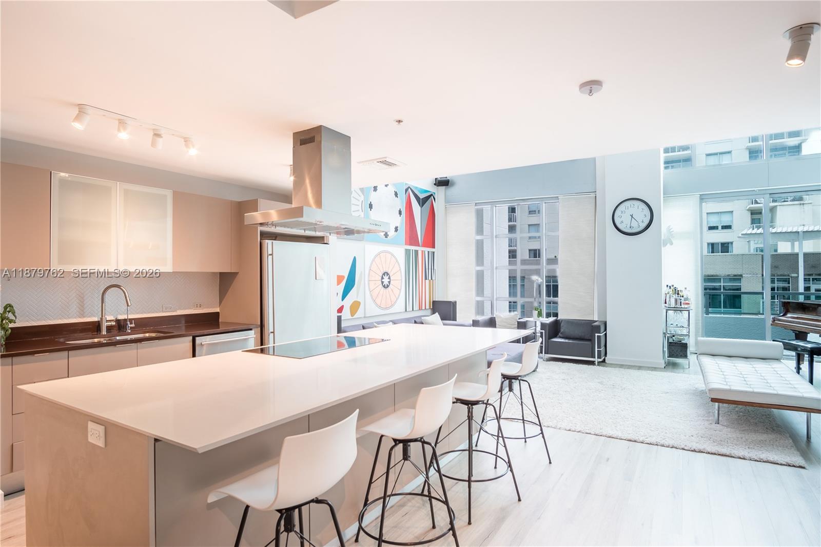 A modern open-concept kitchen and living area features a large island, bar stools, and artwork — 3301 NE 1st Ave # M0501, Miami FL 33137, MIAMI, FL